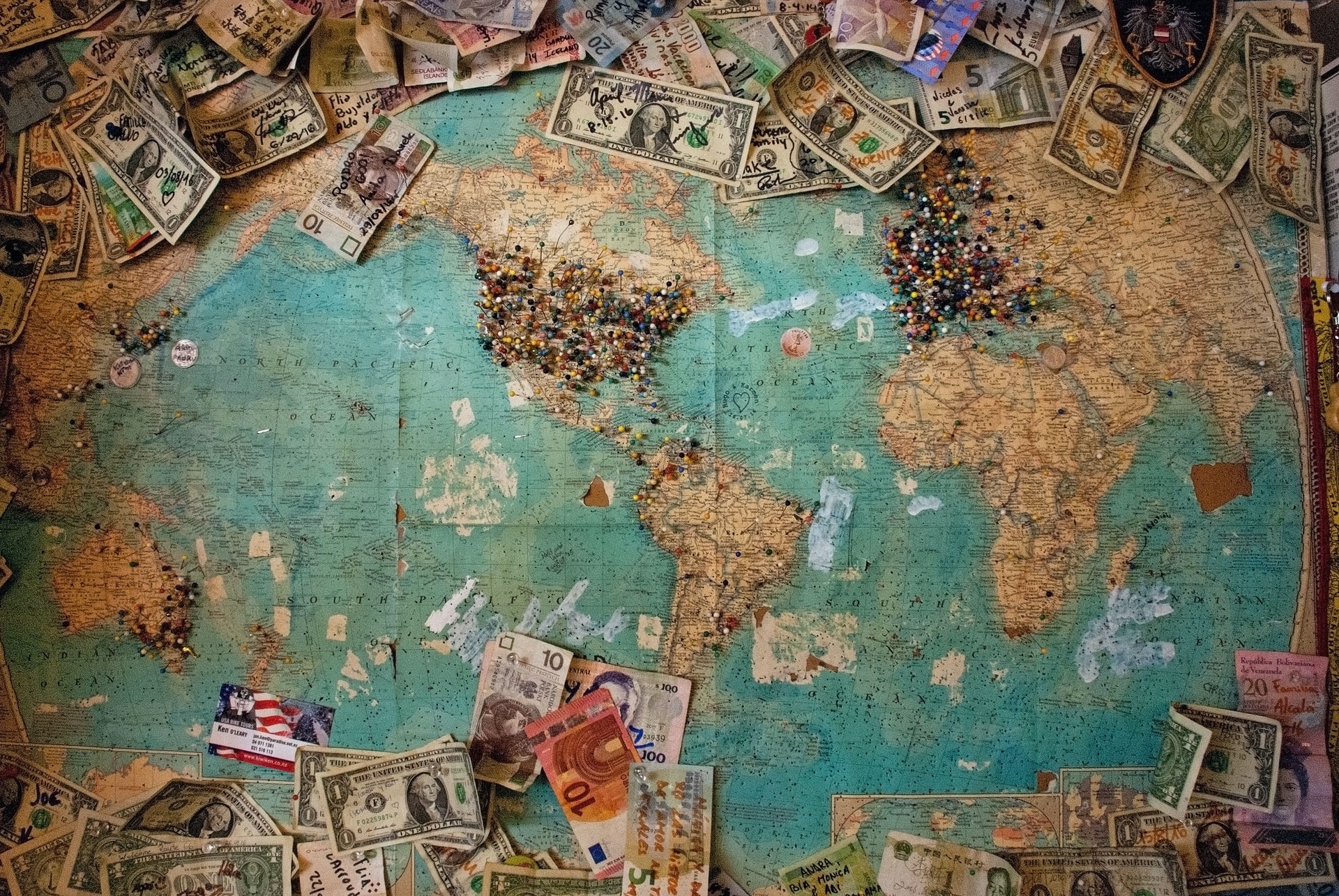 World map surrounded by notes in different currencies